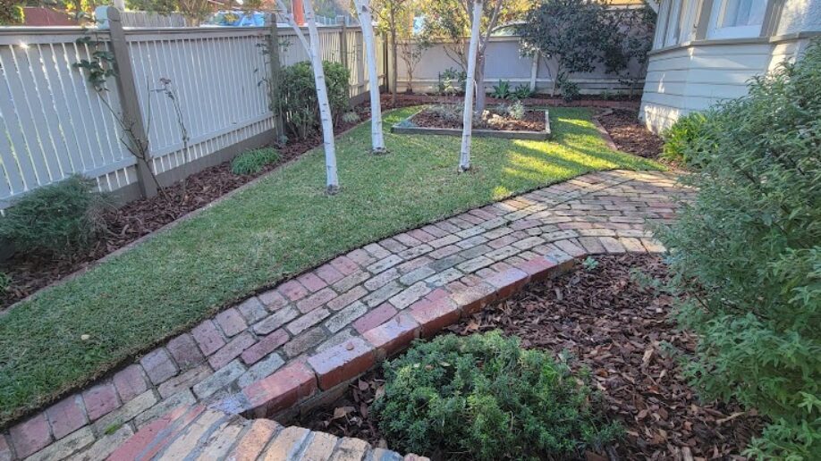 After: Back lawn and path. Grass cut back and edged, beds mulched and the brick path cleared.